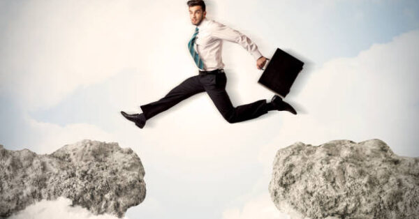 Happy business man jumping over a cliff concept Happy business man jumping over a cliff concept
