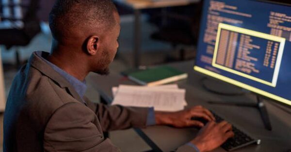 BrainPath Consults High angle view at black IT developer wearing suit and using computer while working on data security project in office