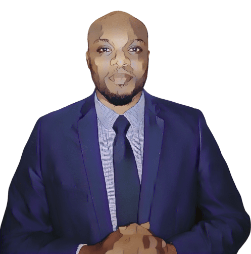 A man wearing a navy blue suit, checkered shirt, and dark tie stands against a plain light background, with his hands clasped together in front of him.